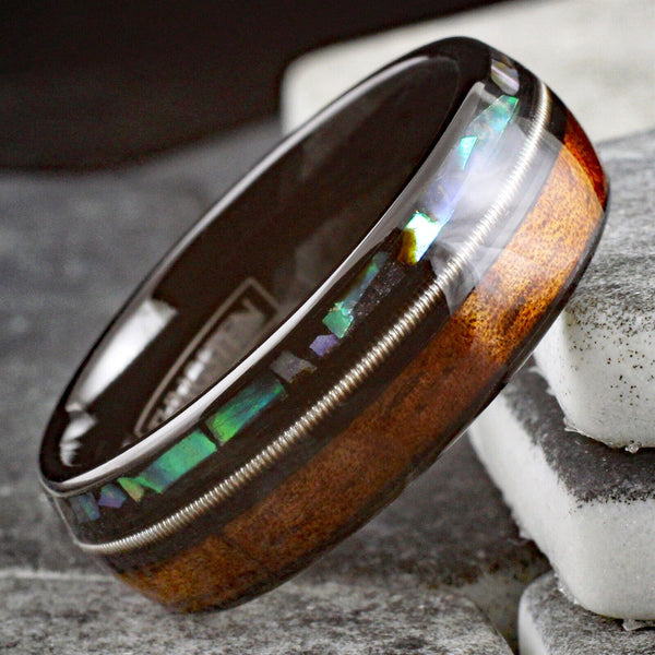 Cool Polished Black Tungsten Low Dome Ring with Silver Guitar String Between Iridescent Abalone And Whiskey Barrel Oak Wood Inlays.