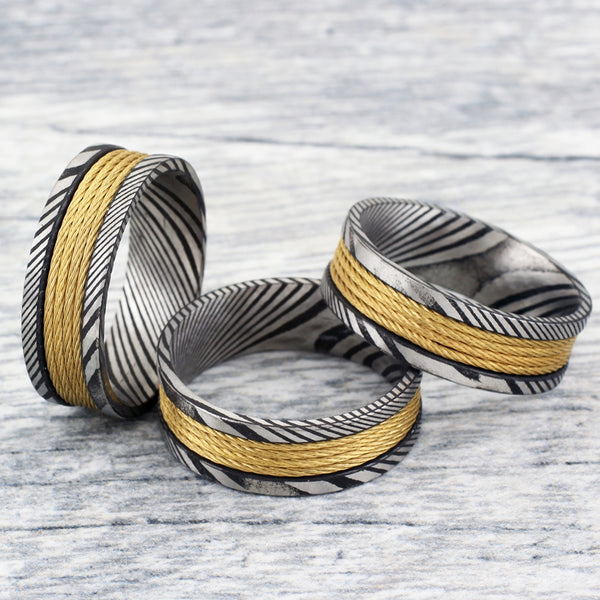 Antiqued black & silver Damascus Steel band ring w/ 4 gold stainless steel cable inlays | Group photo